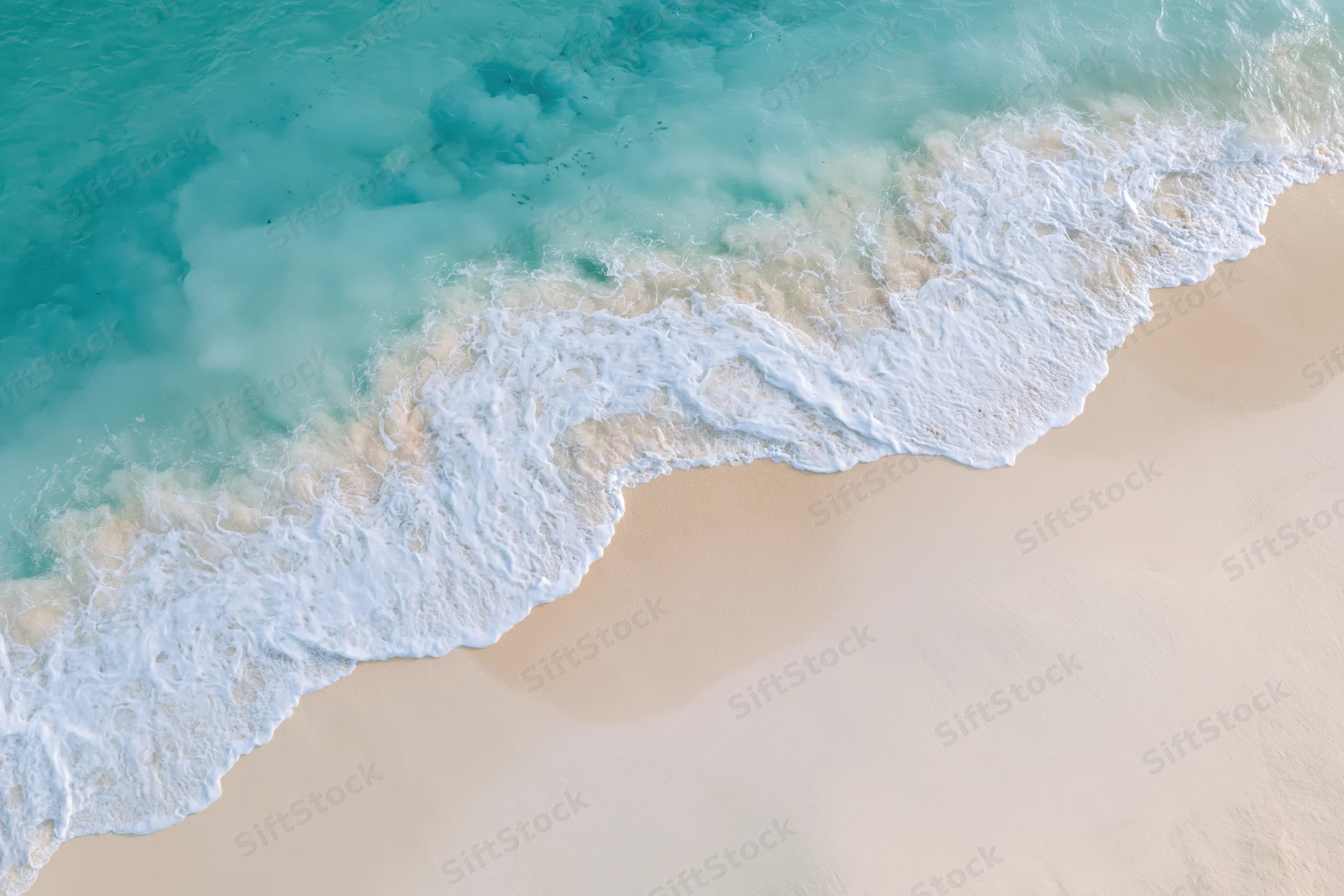 Aerial top-down view of turquoise ocean waves breaking on a sandy tropical beach