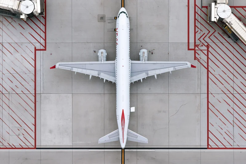 White commercial passenger jet parked at airport gate viewed from directly above