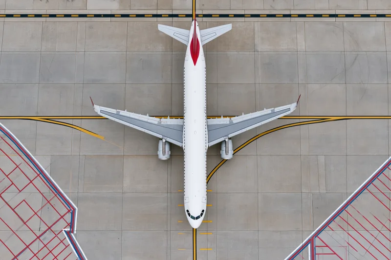 White commercial passenger jet viewed from above on airport tarmac