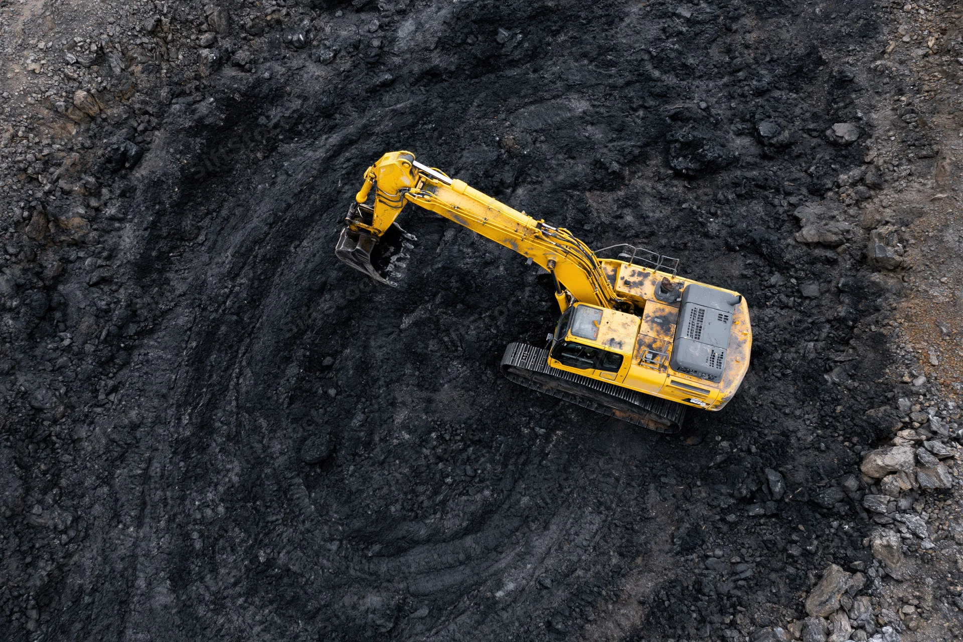 Yellow excavator digging in open-pit coal mine from above