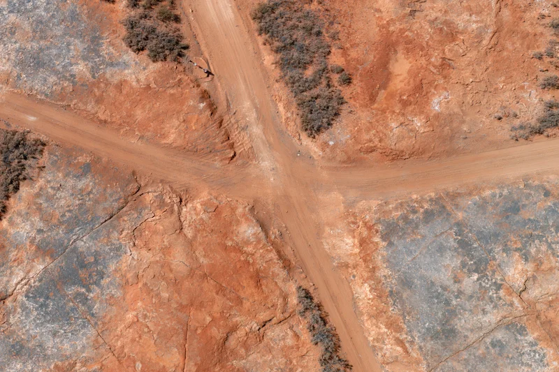 Aerial top-down view of intersecting dirt roads in a red arid desert landscape