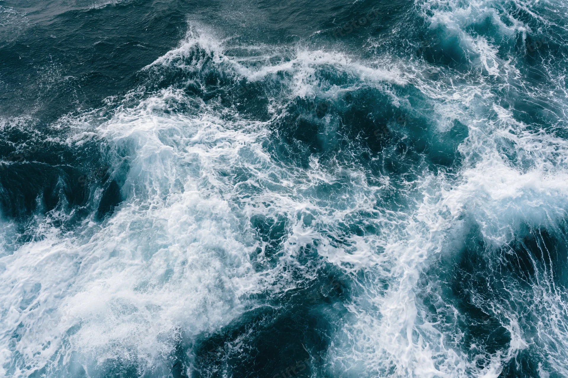 Aerial top-down view of churning deep ocean water with white foam