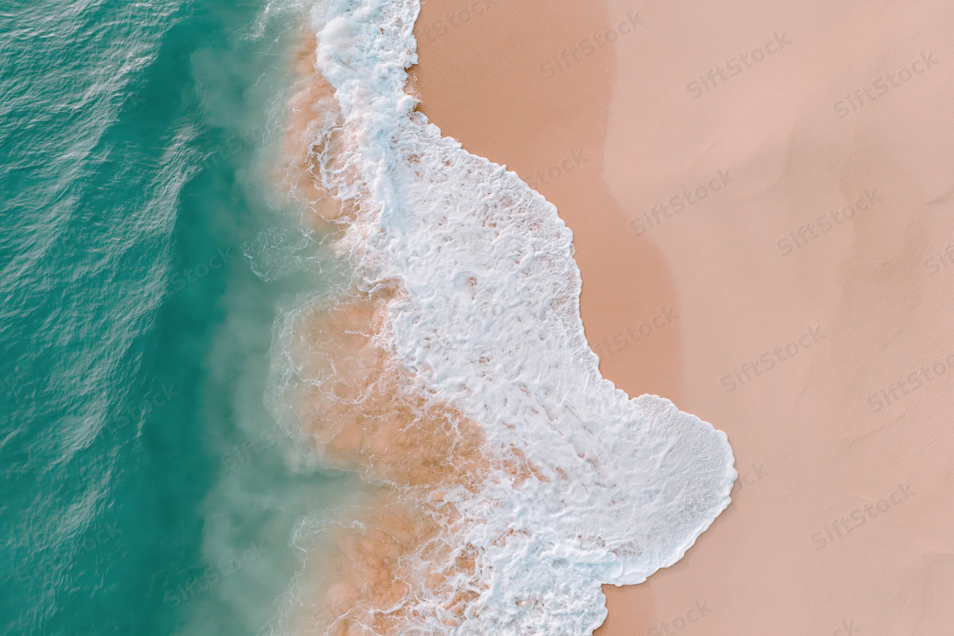 Aerial top-down view of ocean waves breaking on a wide sandy beach