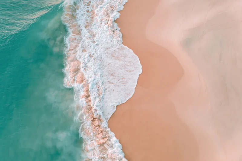 Aerial top-down view of ocean waves meeting a wide sandy beach