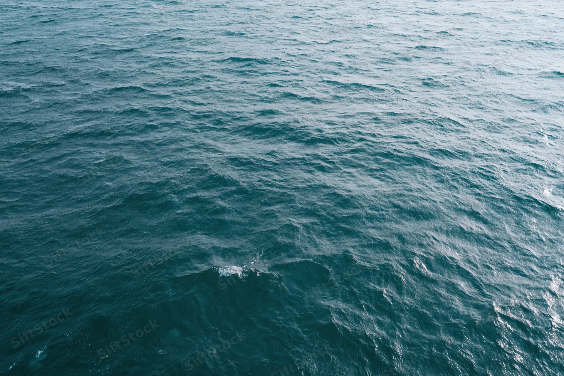 Aerial top-down view of open ocean surface with small wind-driven waves