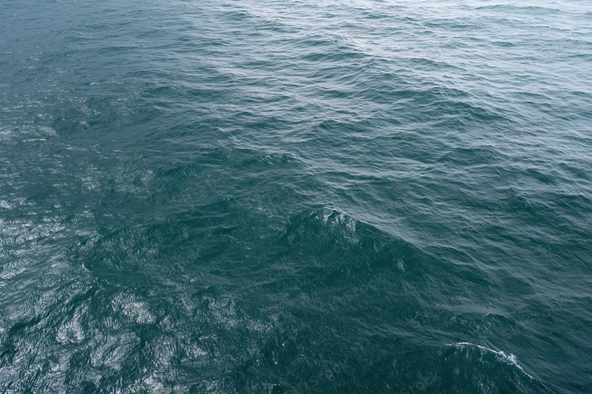 Aerial top-down view of open ocean surface with small wind-driven waves and ripples