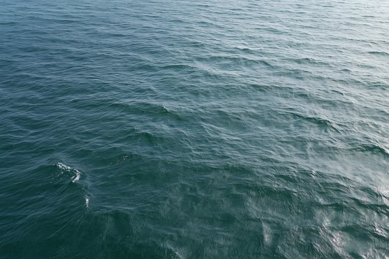 Aerial top-down view of open ocean surface with small wind-driven waves and ripples