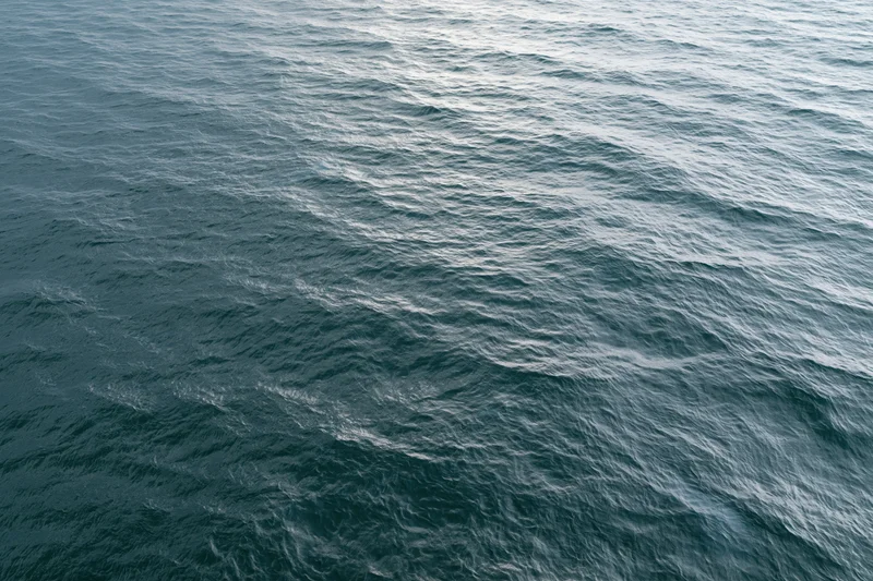 Aerial top-down view of open ocean surface with small wind-driven ripples and light reflections