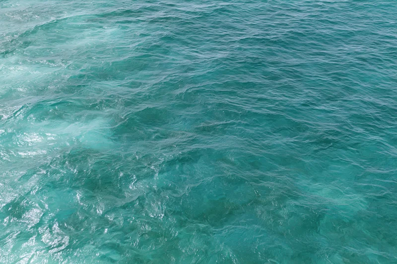 Aerial top-down view of open ocean surface with small wind-rippled waves and turquoise water