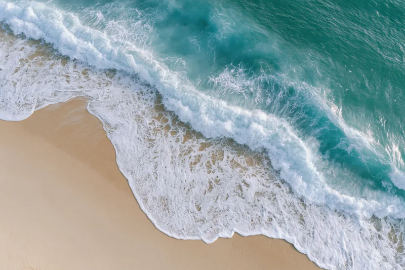 Aerial top-down view of ocean waves washing onto sandy beach