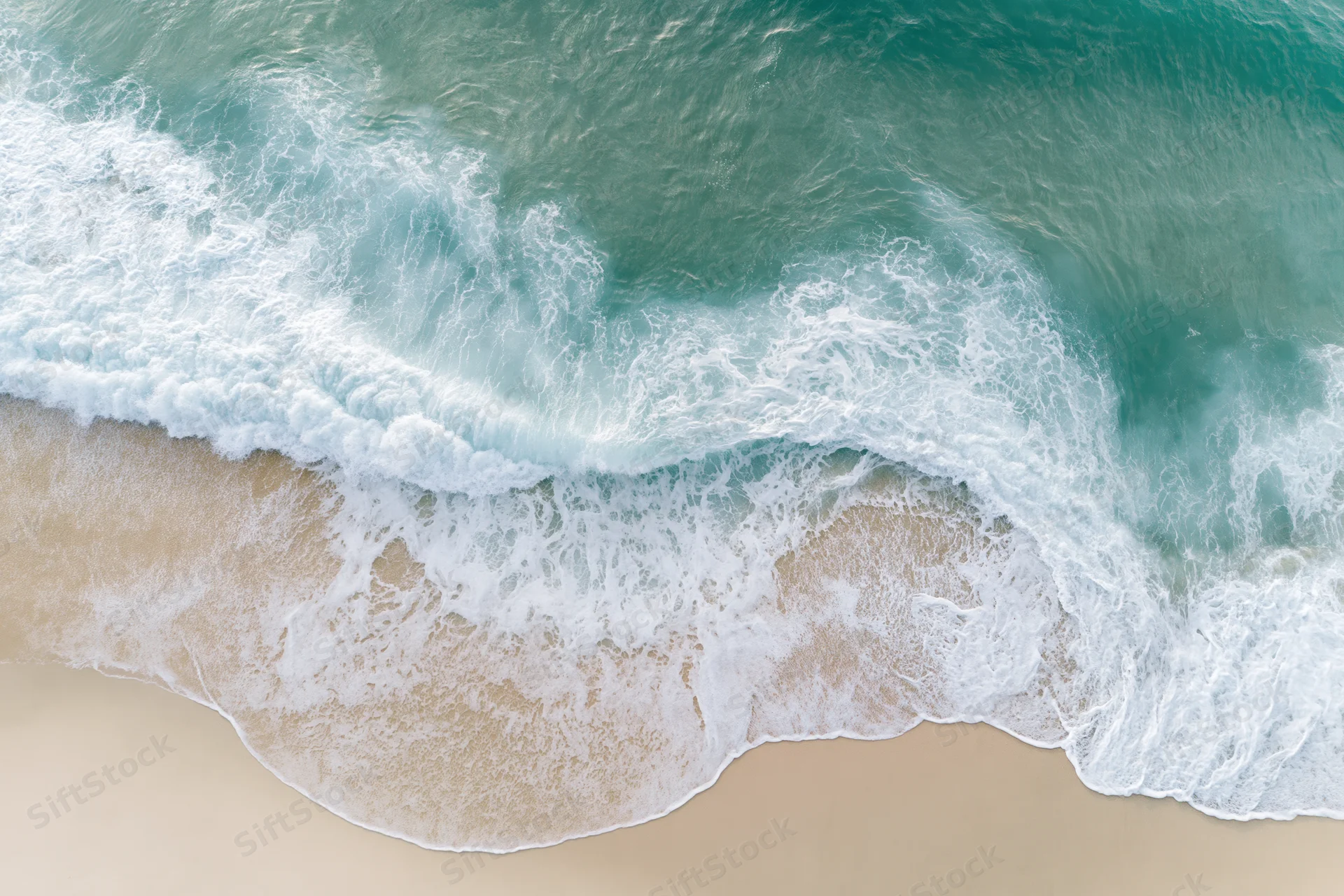 Aerial top-down view of ocean waves breaking onto sandy beach