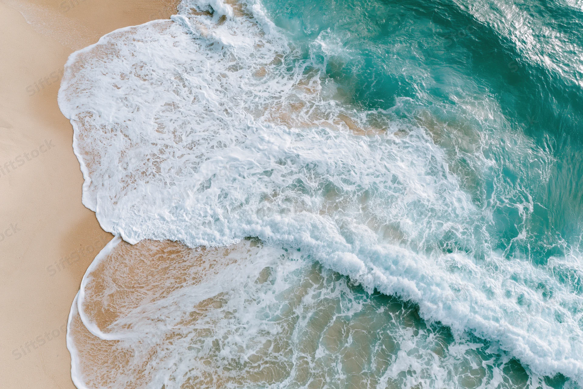 Aerial top-down view of turquoise ocean waves washing onto sandy beach