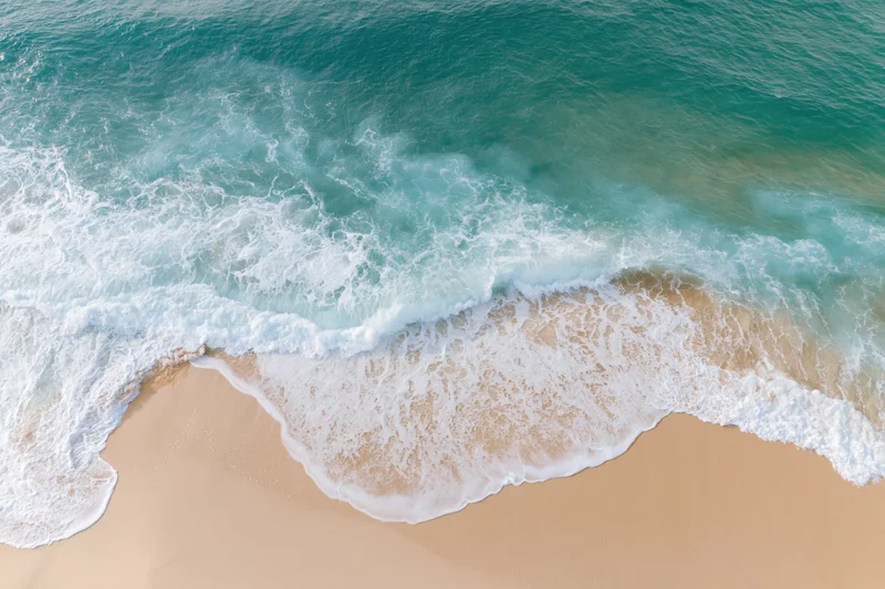 Aerial top-down view of ocean waves washing onto sandy beach