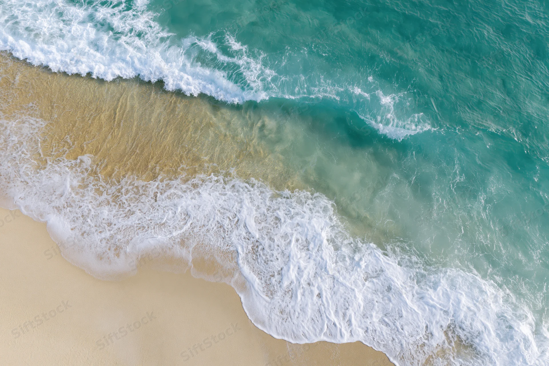 Aerial top-down view of turquoise ocean waves breaking on sandy beach