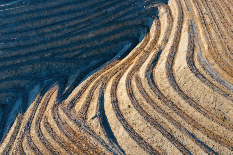 Aerial top-down view of terraced vineyard hillsides showing soil patterns and tractor tracks