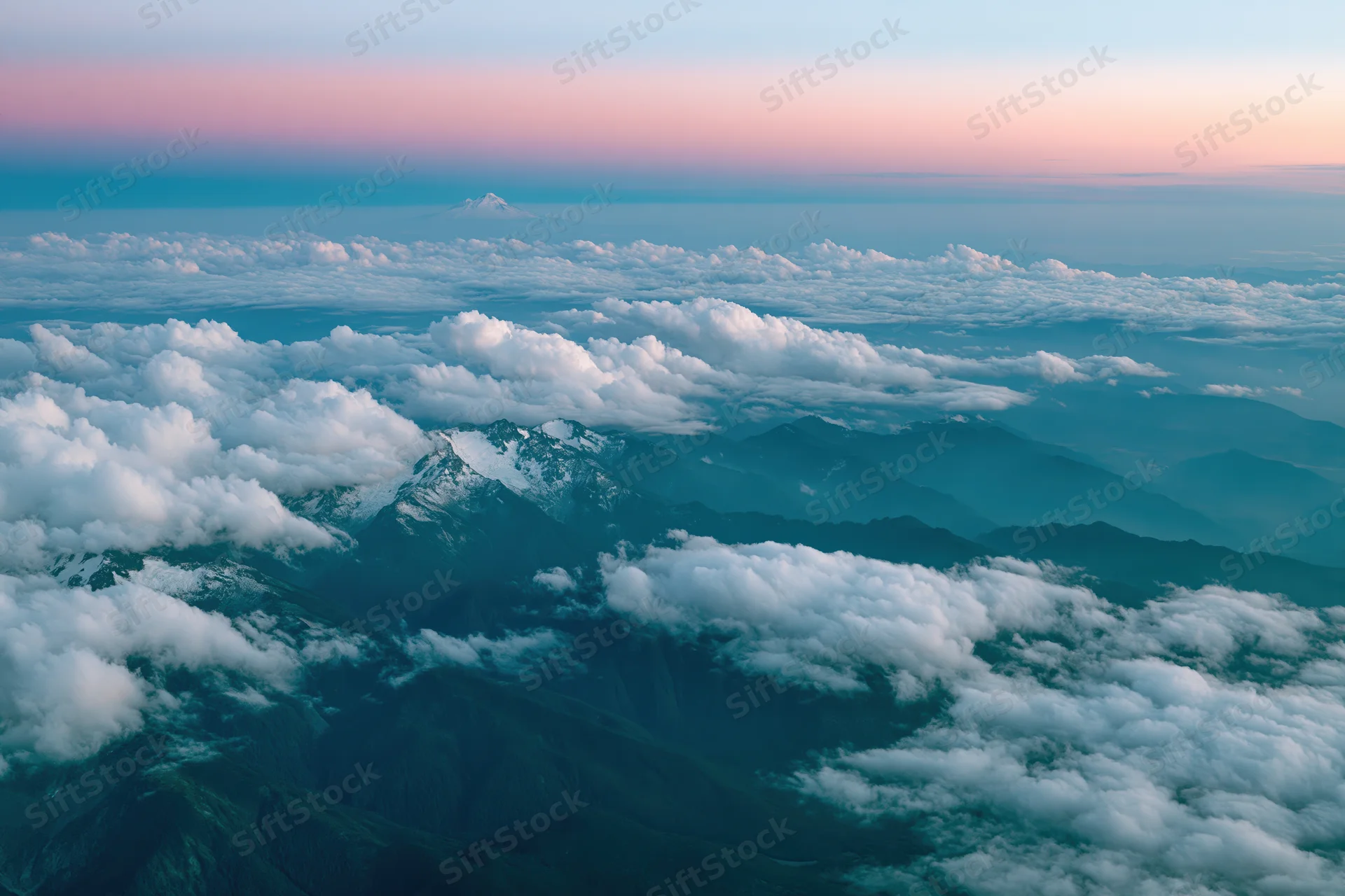 Aerial view of snow-capped mountains and clouds from airplane window at twilight