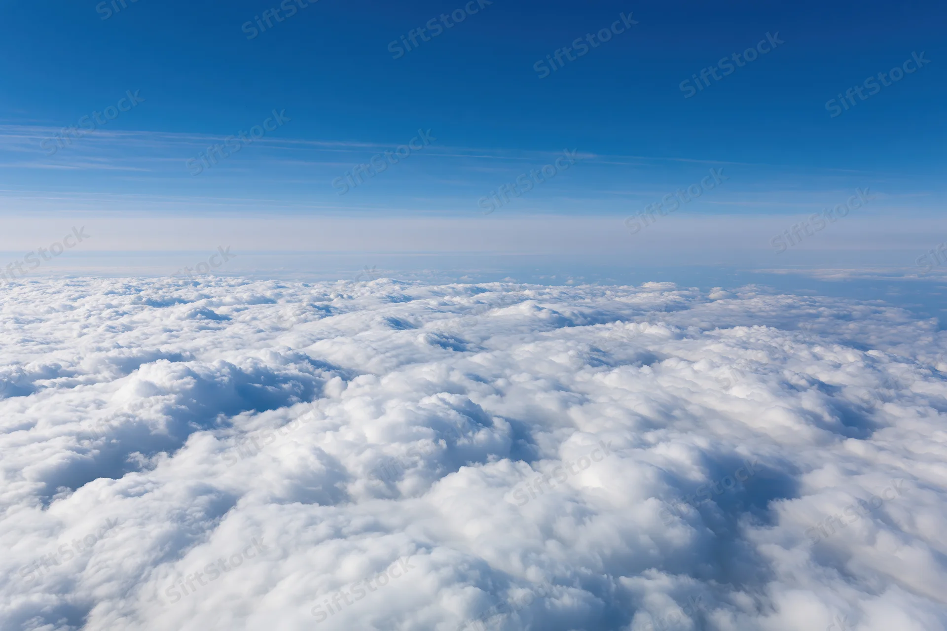 Aerial view of dense white cumulus clouds below a clear blue sky