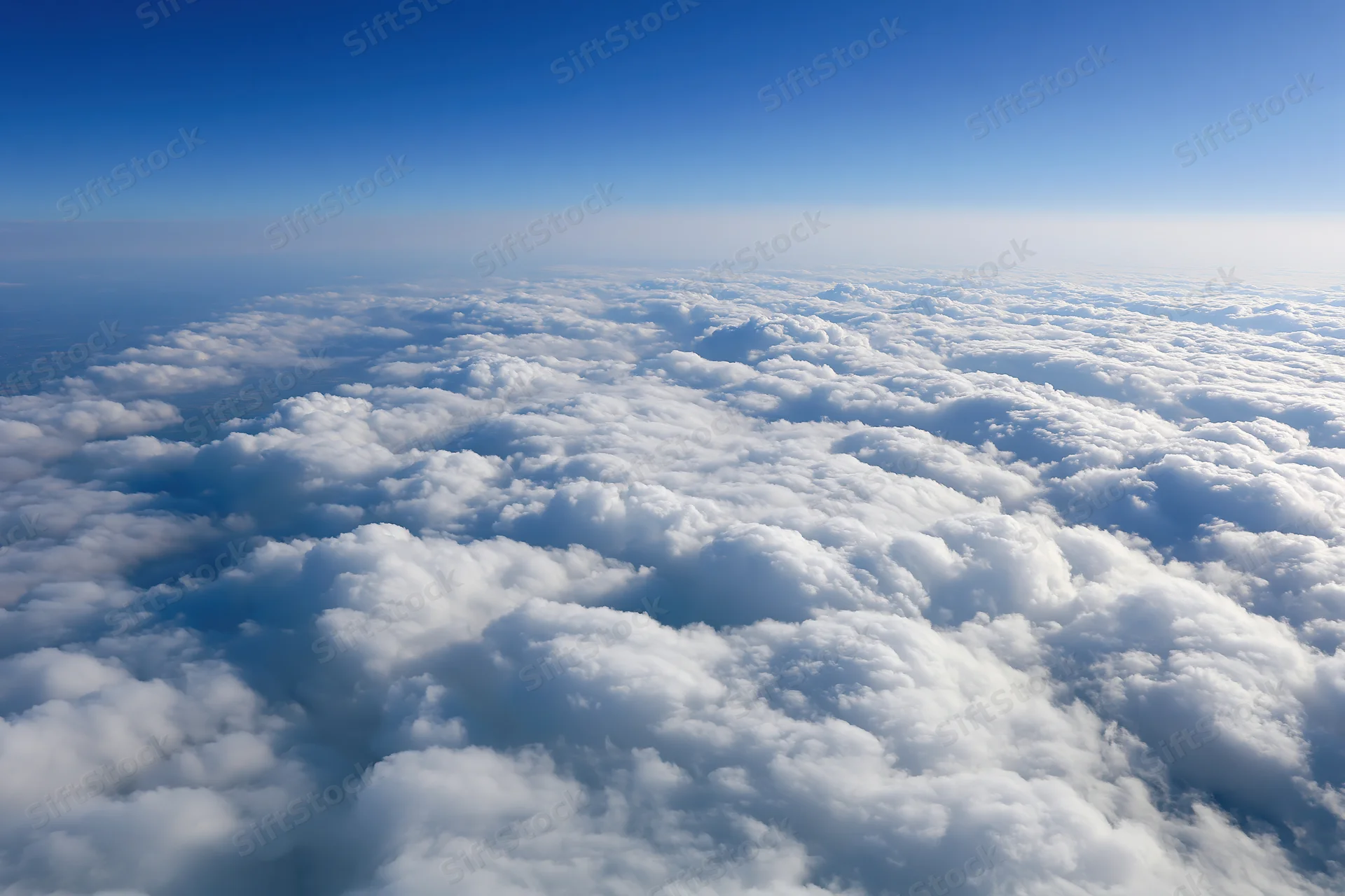 Aerial view of dense white cumulus clouds stretching to the horizon under a clear blue sky