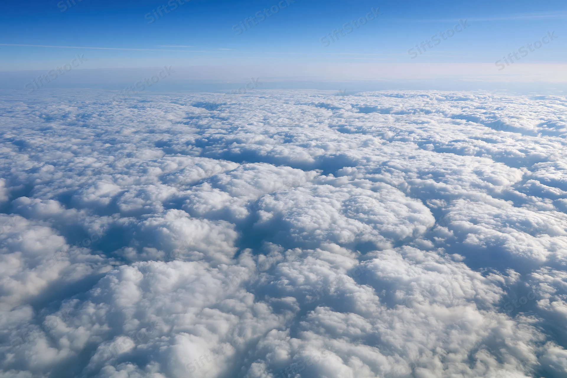 Aerial view of dense white cumulus clouds stretching to the horizon under a clear blue sky