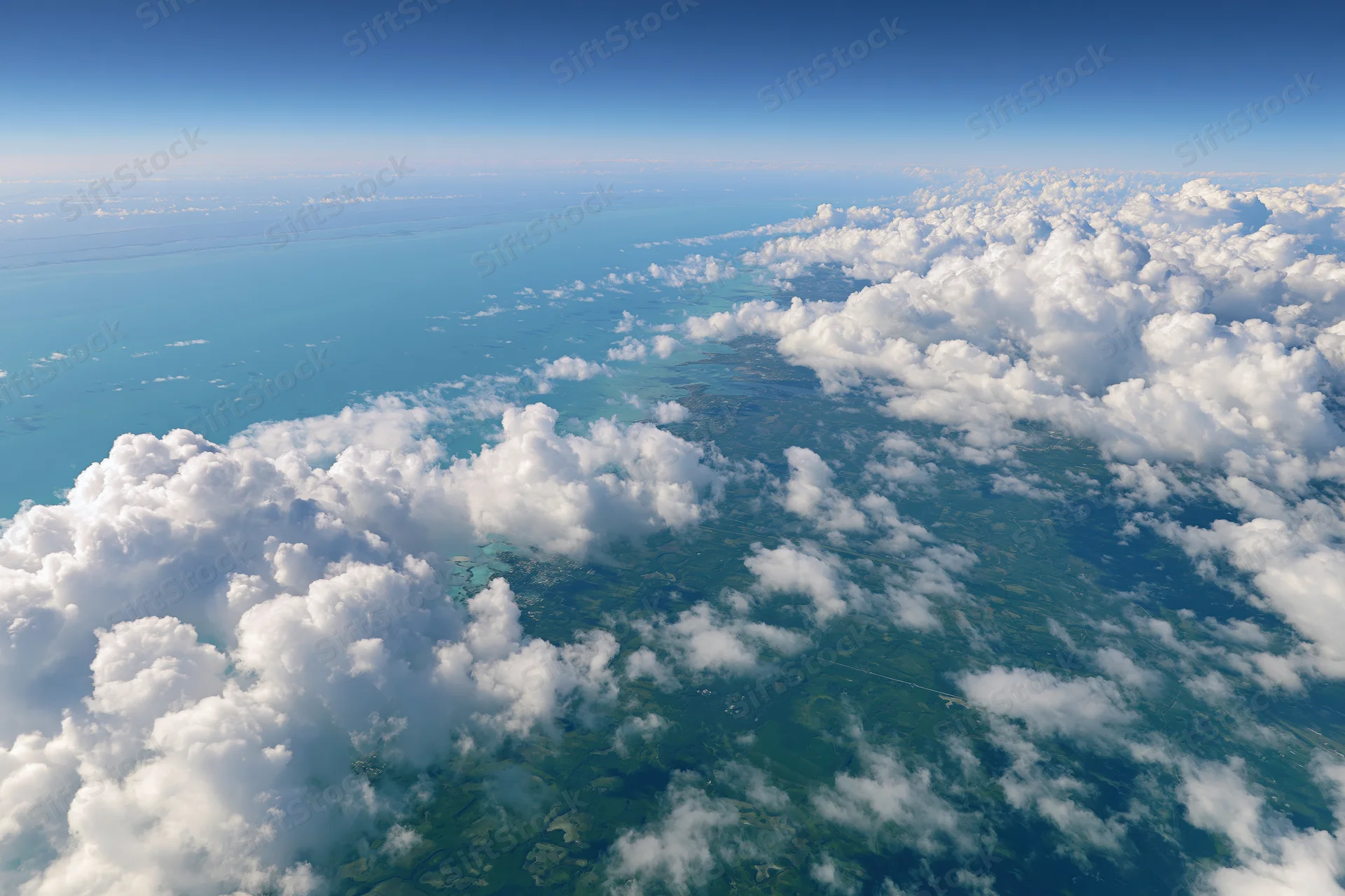 Aerial view of coastline and turquoise ocean from above clouds