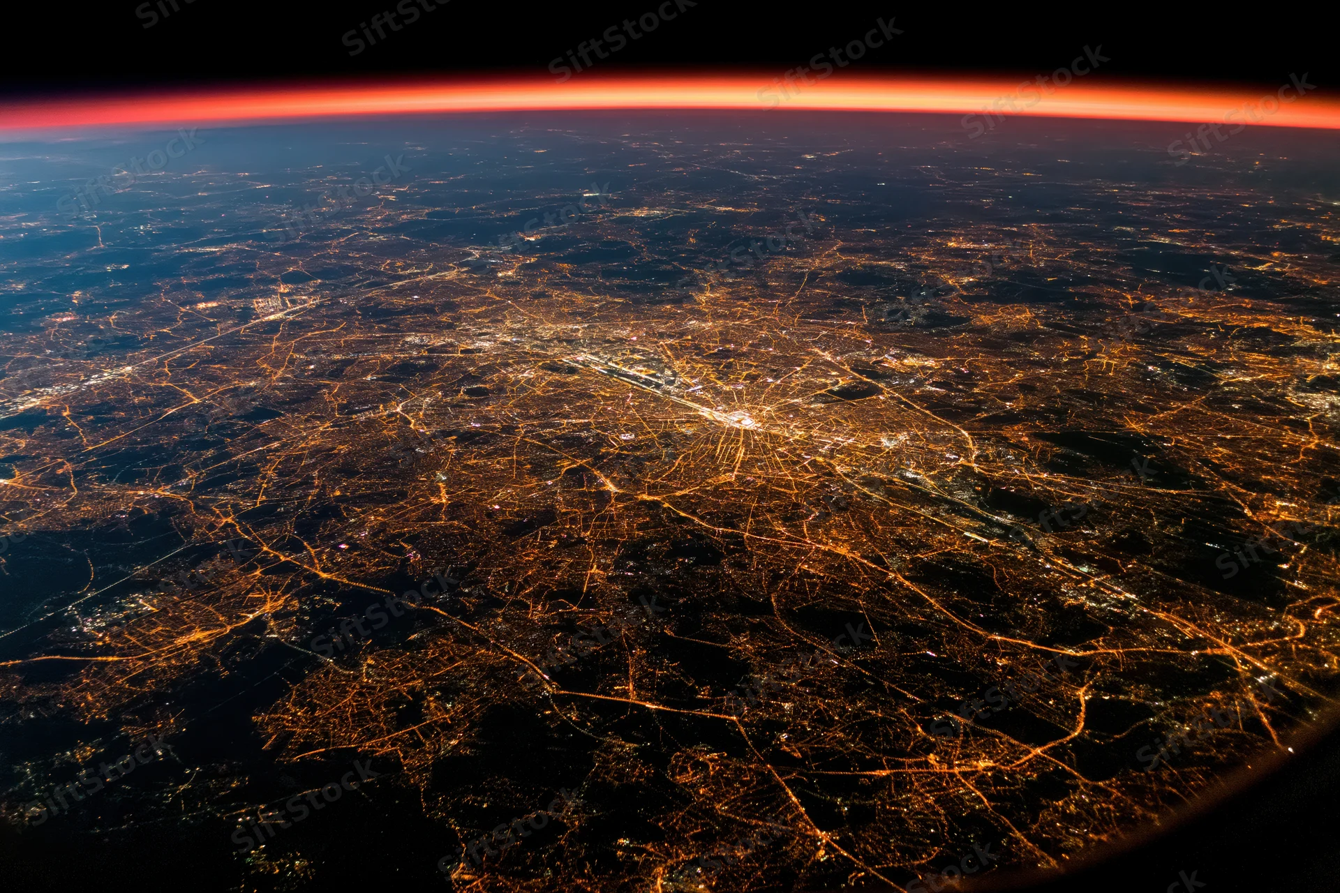 Aerial view of a european city at night from space showing illuminated roads and buildings