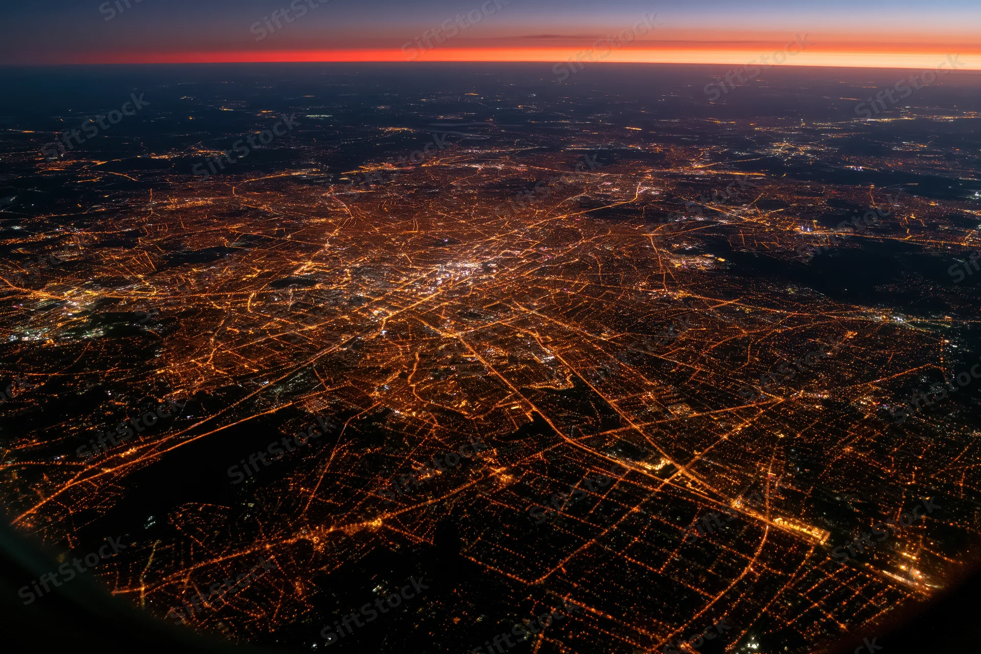 Aerial view of a european city at night showing illuminated streets and urban grid from airplane window