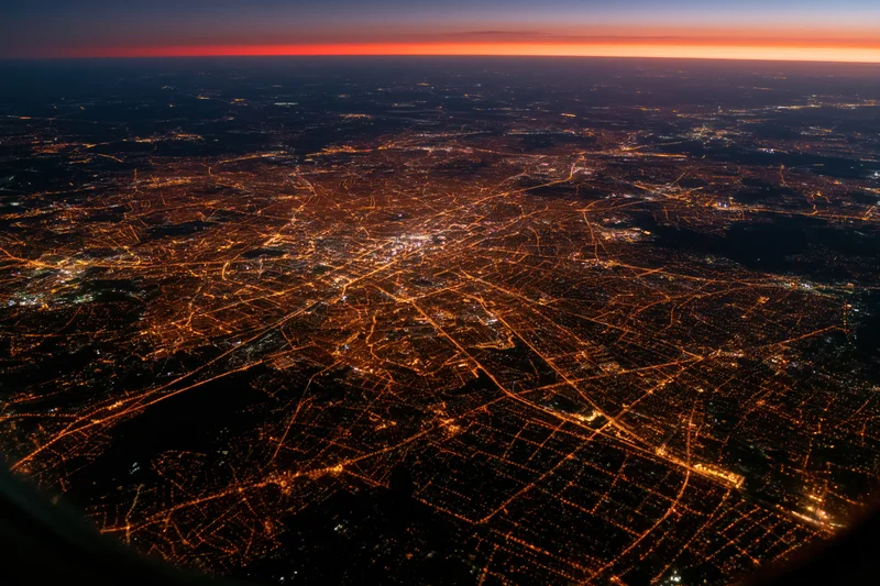 Aerial view of a european city at night showing illuminated streets and urban grid from airplane window