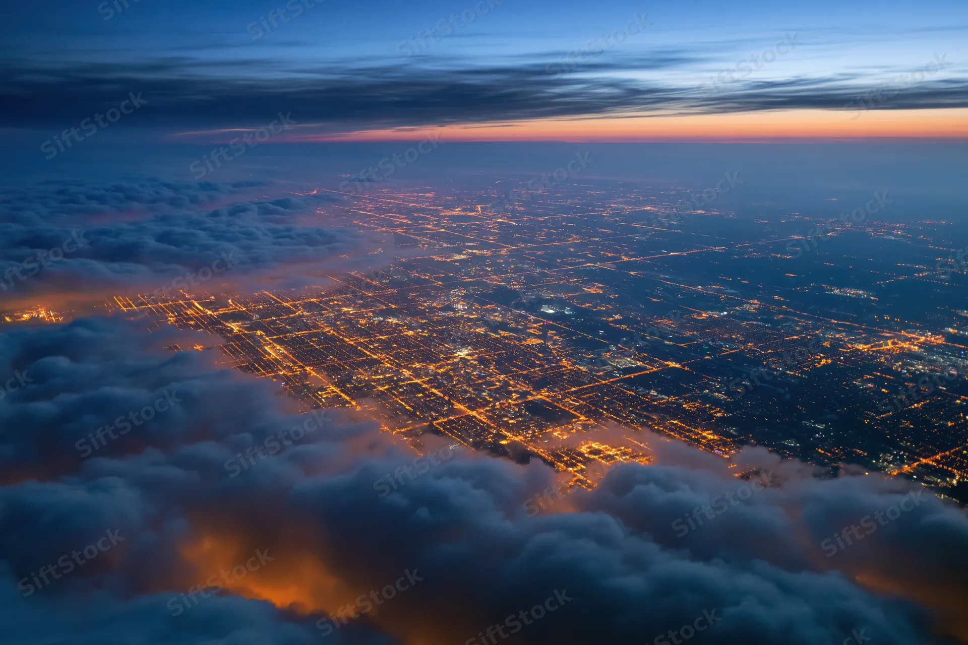 Aerial view of a sprawling city at night from above clouds