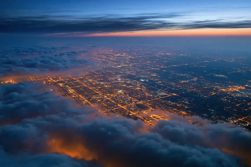 Aerial view of a sprawling city at night from above clouds