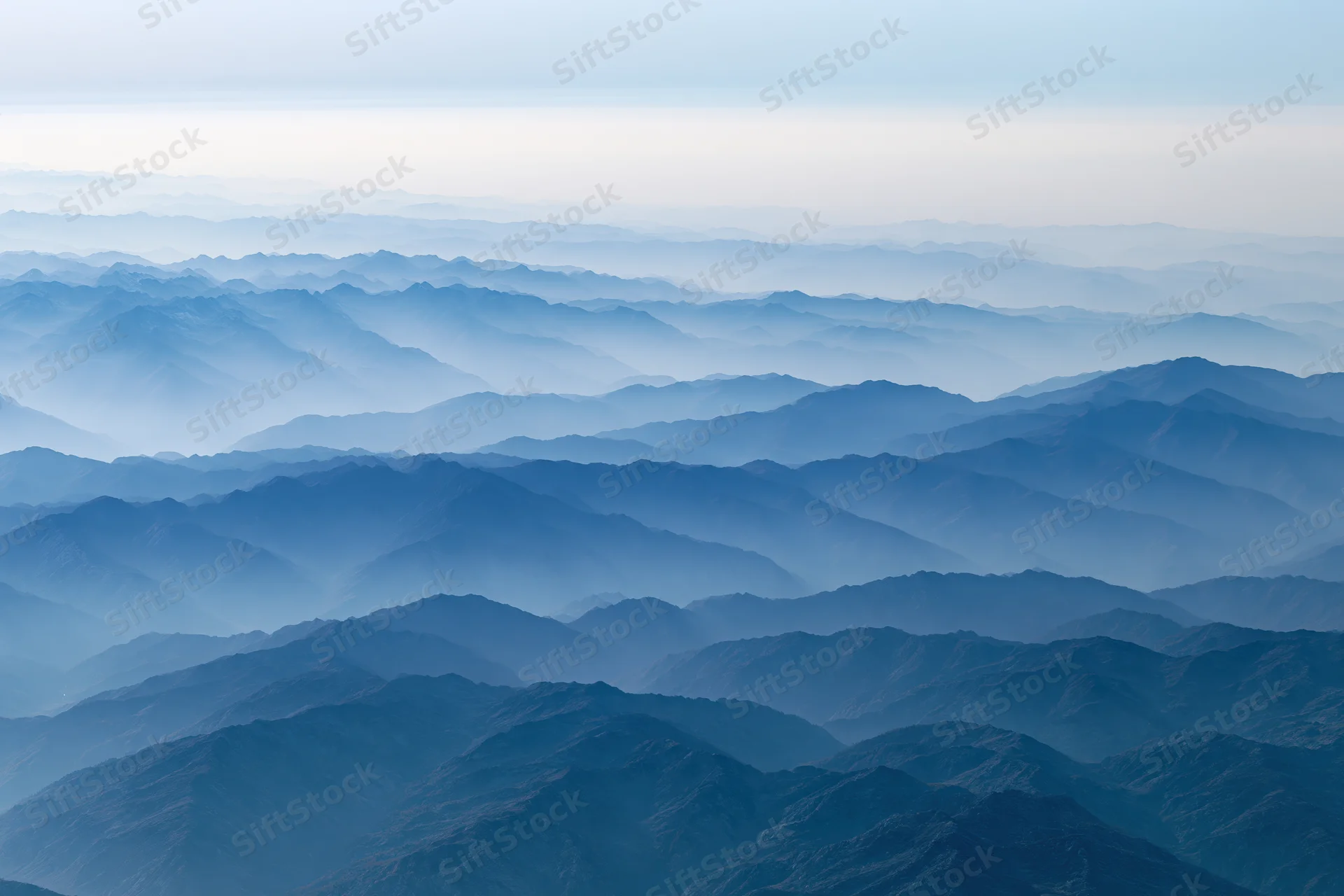 Aerial view of layered mountain ridges receding into haze