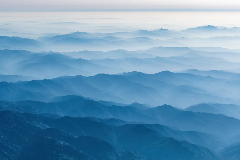 Aerial view of layered mountain ridges receding into haze