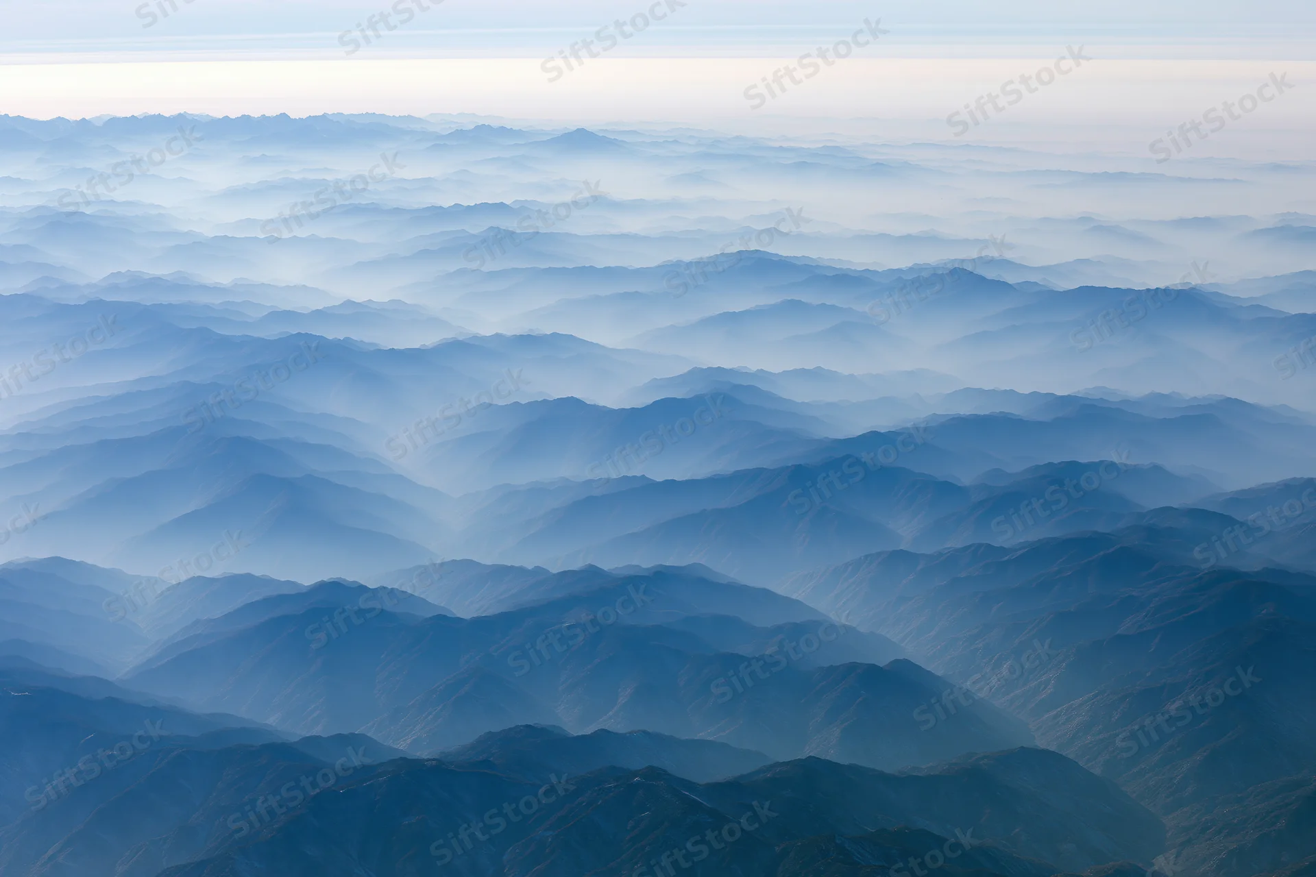 Aerial view of layered mountain ridges receding into haze
