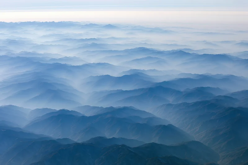 Aerial view of layered mountain ridges receding into haze