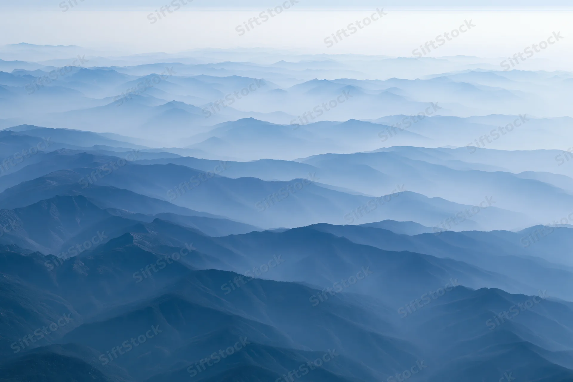 Aerial view of layered mountain ridges receding into haze