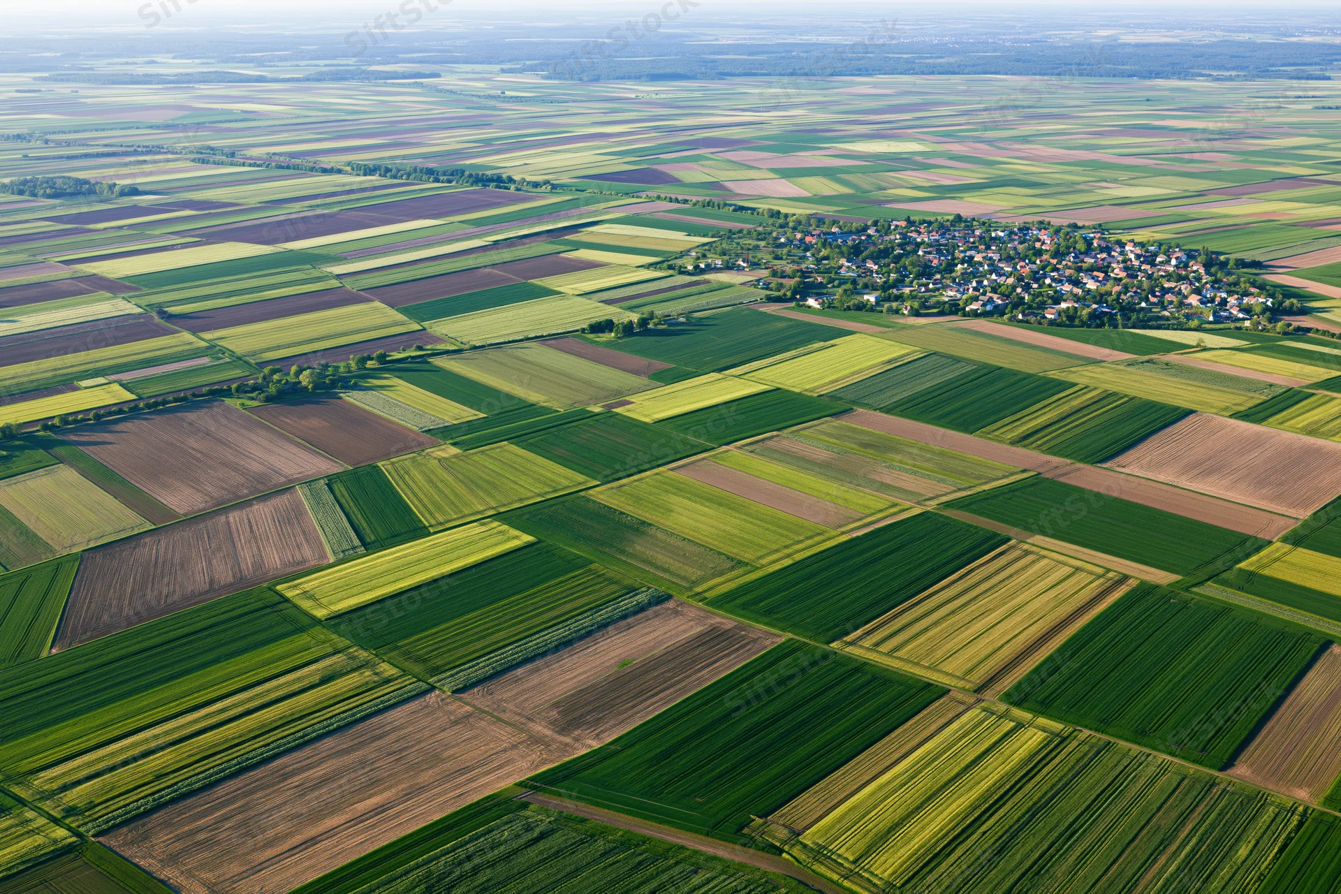 Aerial view of patchwork agricultural fields stretching to the horizon in rural countryside