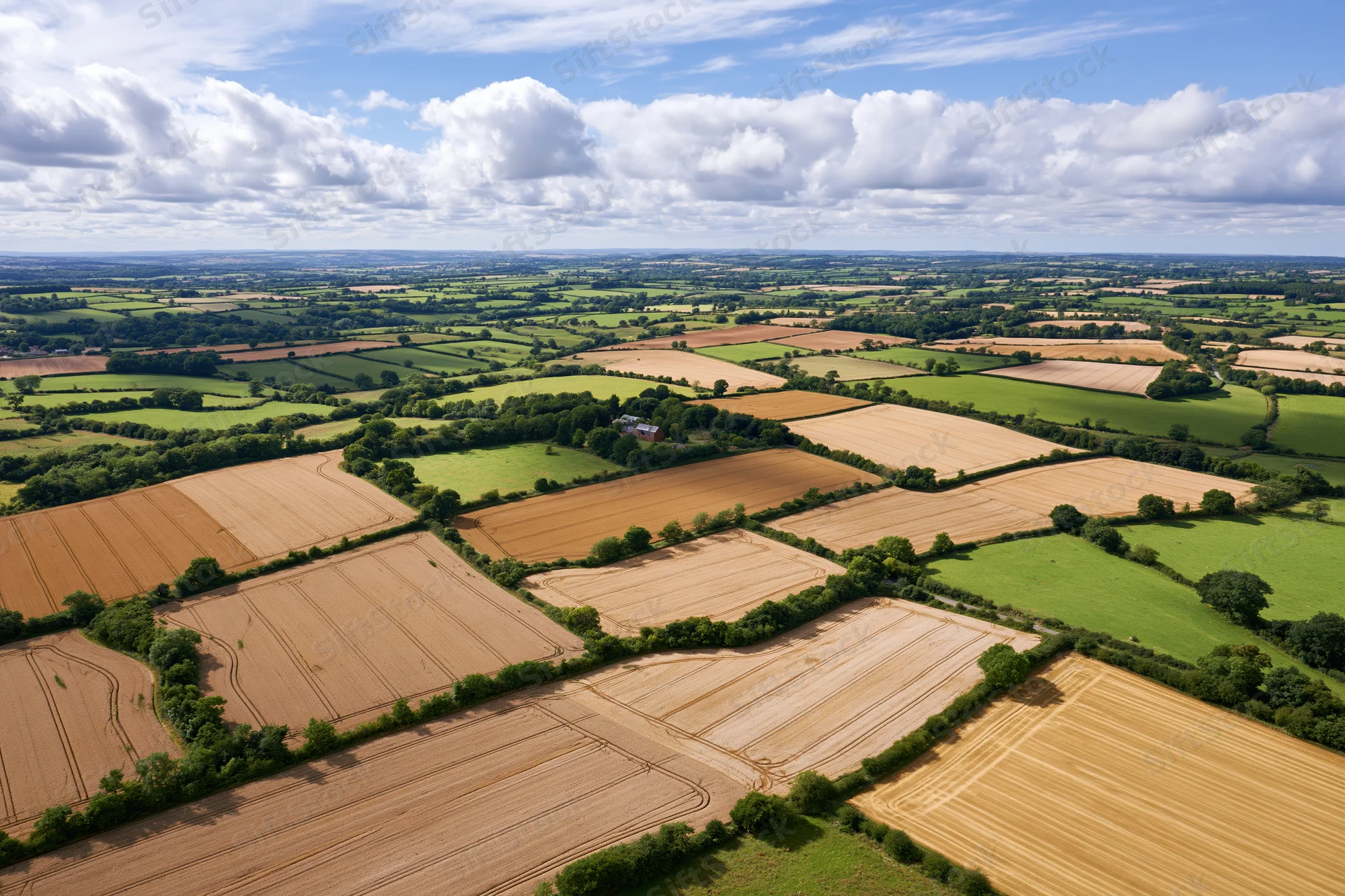 Aerial view of patchwork farmland in the English countryside under a partly cloudy sky