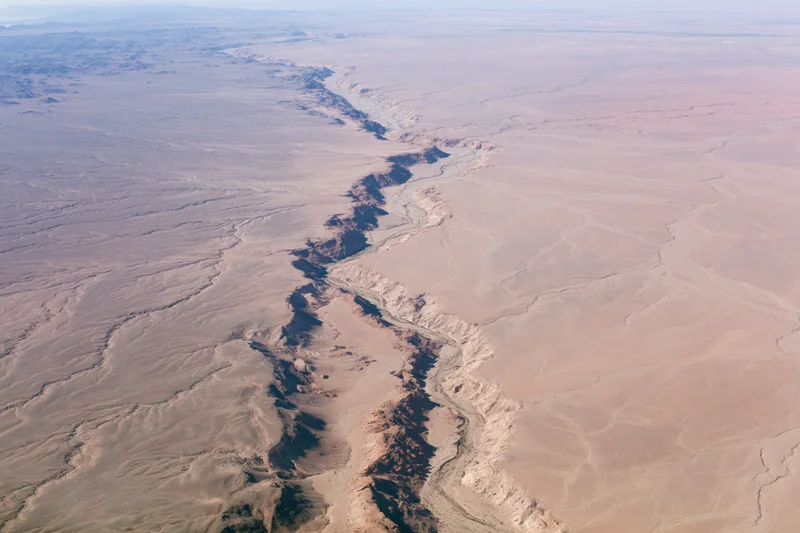 Aerial view of a vast arid desert landscape with a deep canyon cutting through the terrain