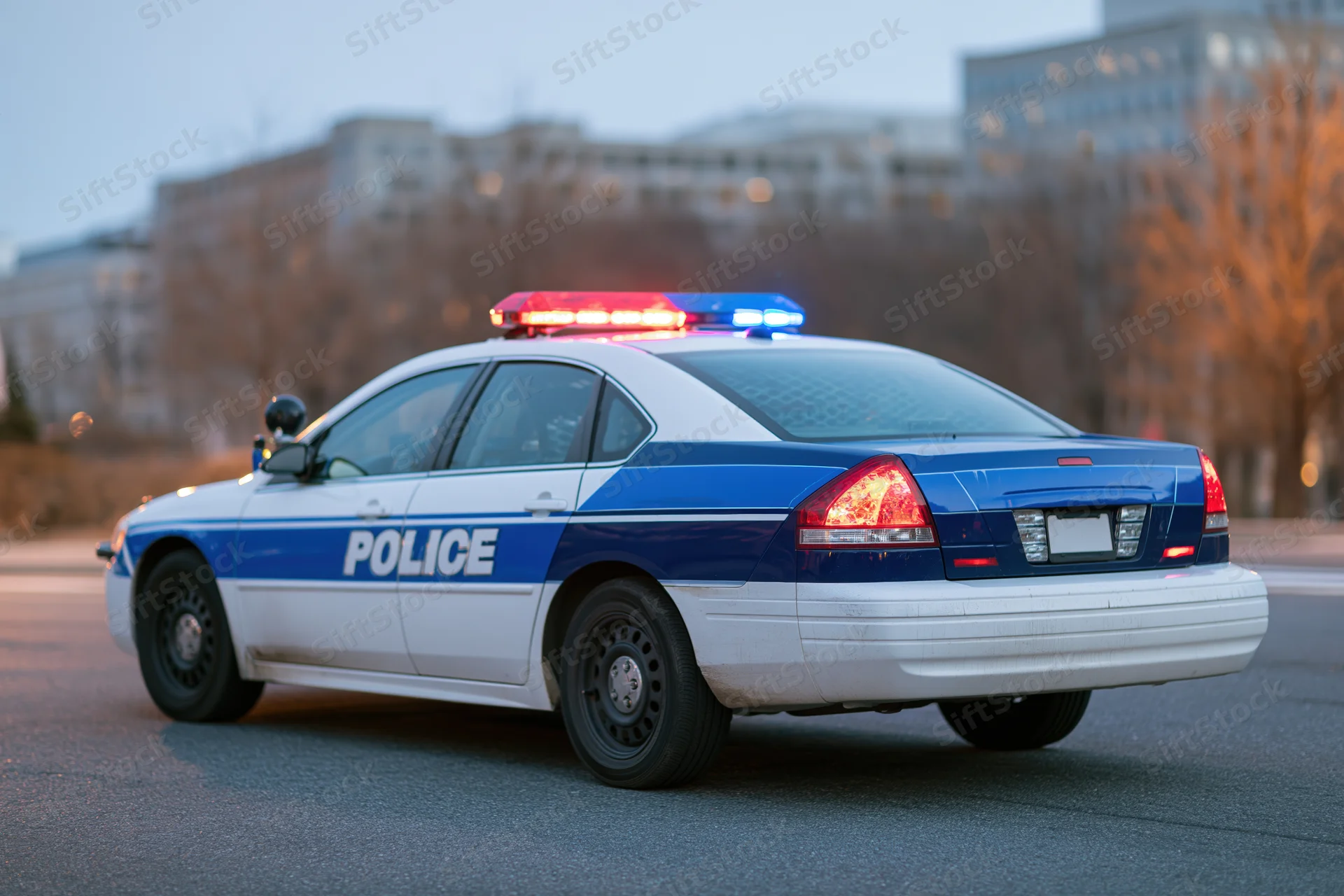 Police patrol car with flashing emergency lights on city street at dusk