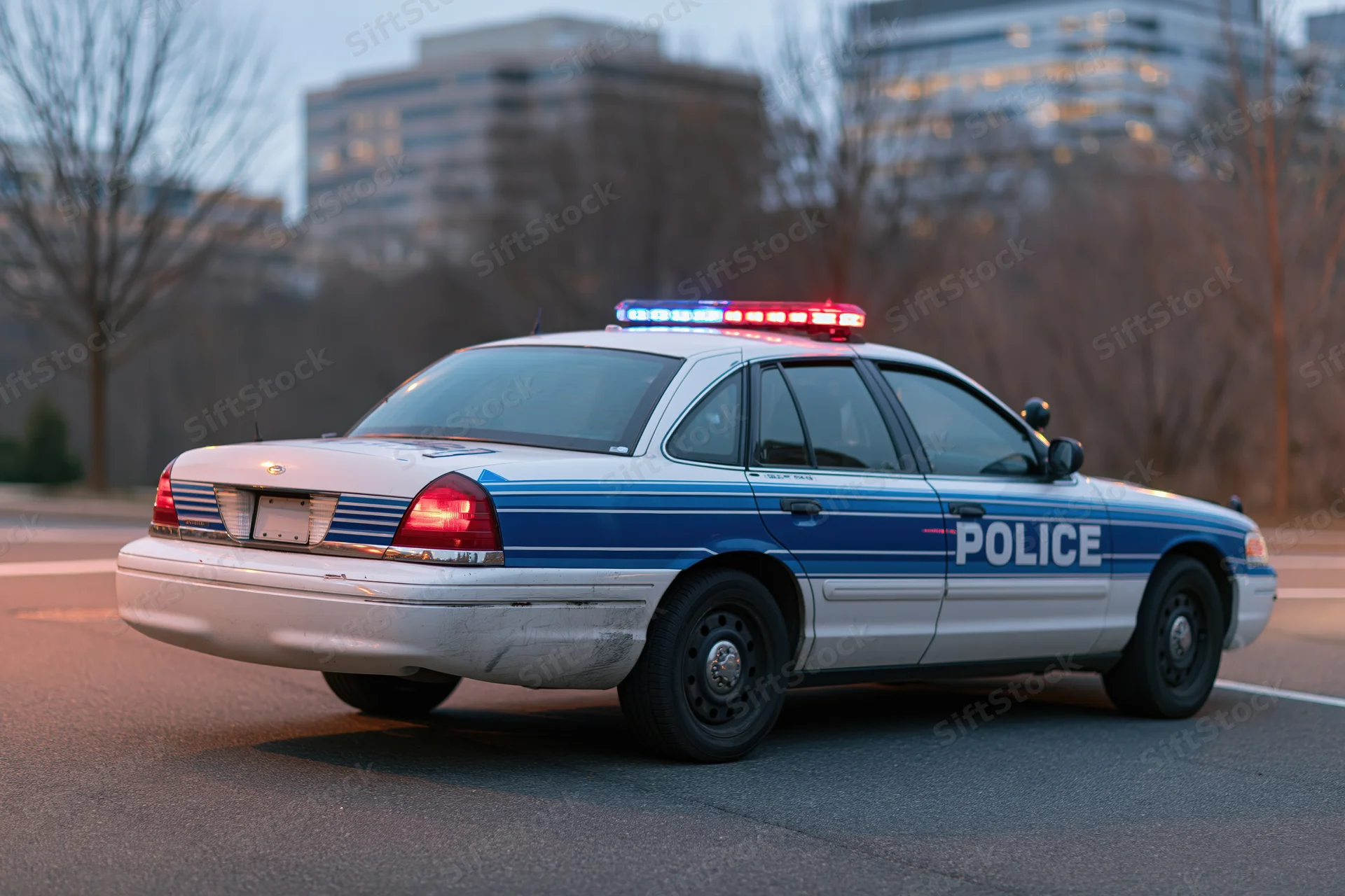 Police patrol car with emergency lights activated on city street at dusk