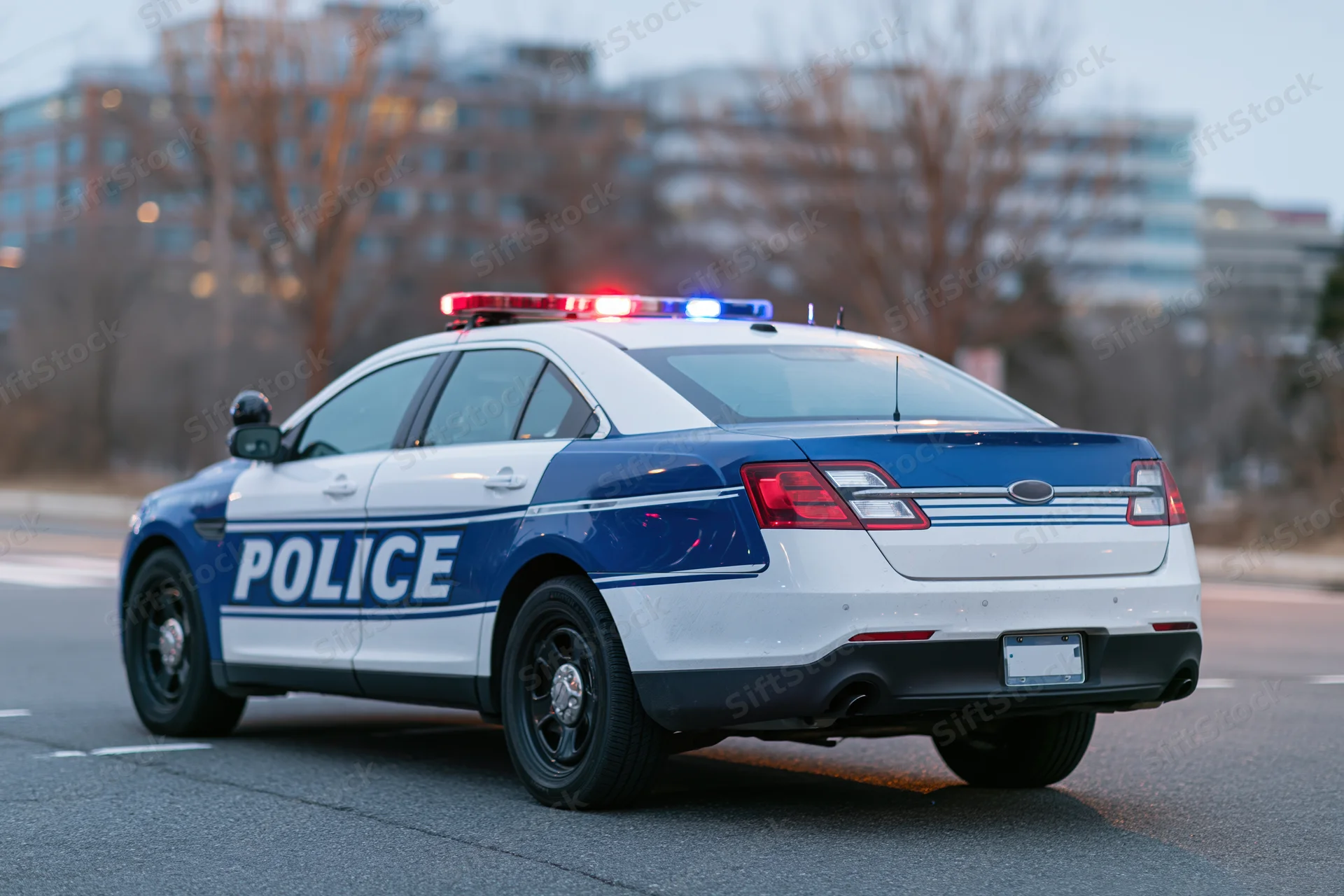 Police patrol car with flashing emergency lights on city street at dusk