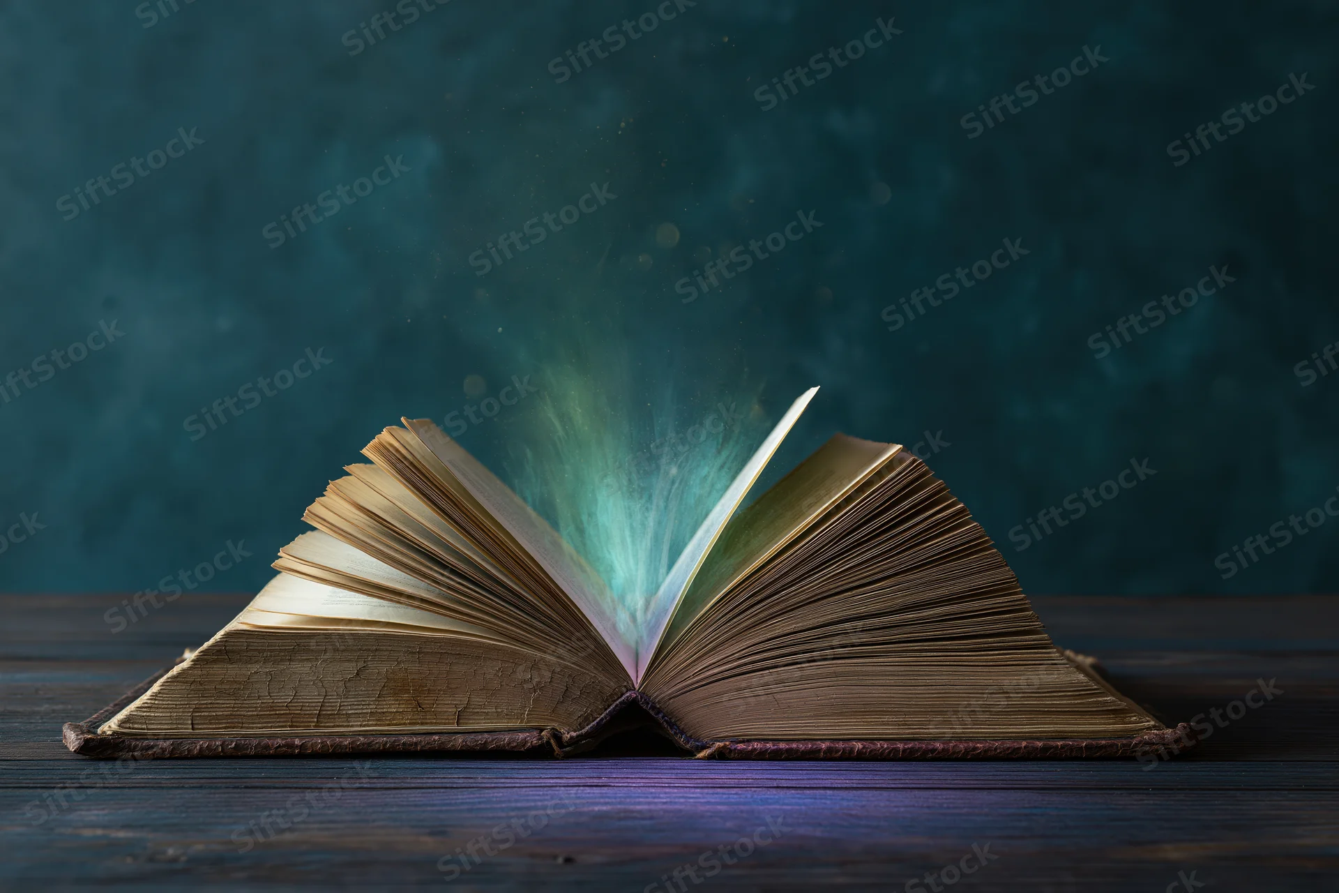 Open old weathered hardcover book glowing with magical light on dark wooden table