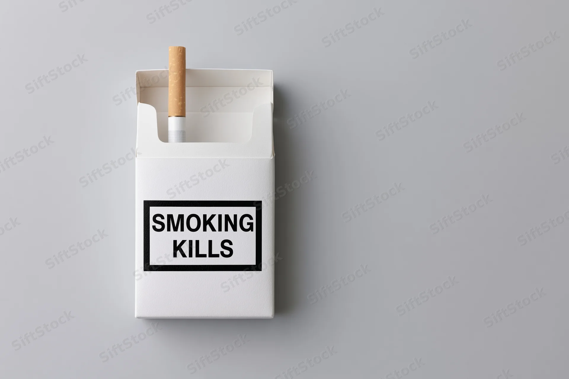 Open white cigarette pack with one cigarette sticking out and smoking kills warning label on gray background