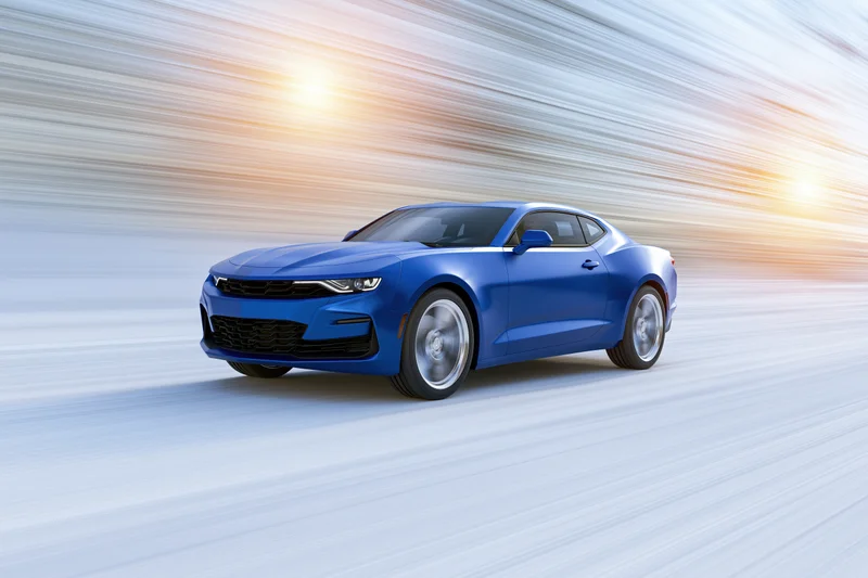 Blue chevrolet camaro muscle car driving at speed on open road with motion blur