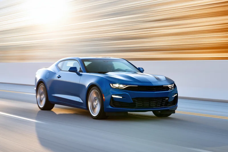 Blue chevrolet camaro muscle car driving at speed on open highway with motion blur