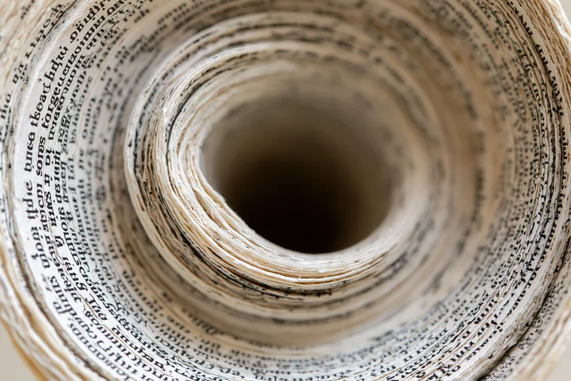 Tightly rolled book pages forming a spiral tunnel with printed text visible in concentric layers