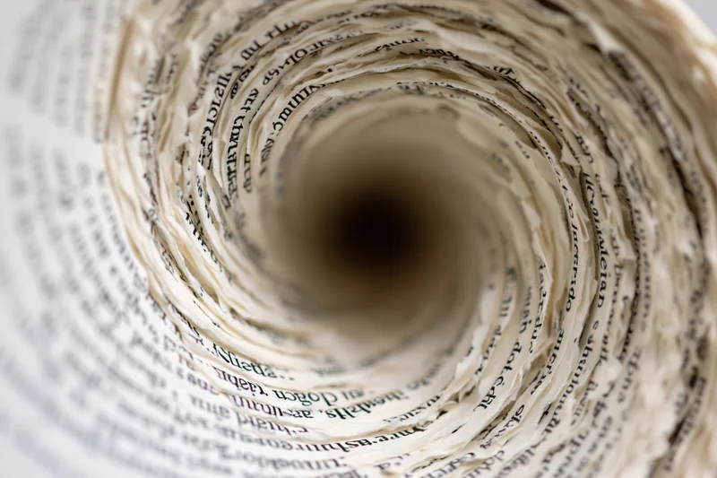 Tightly rolled book pages forming a spiral tunnel with printed text visible along the edges