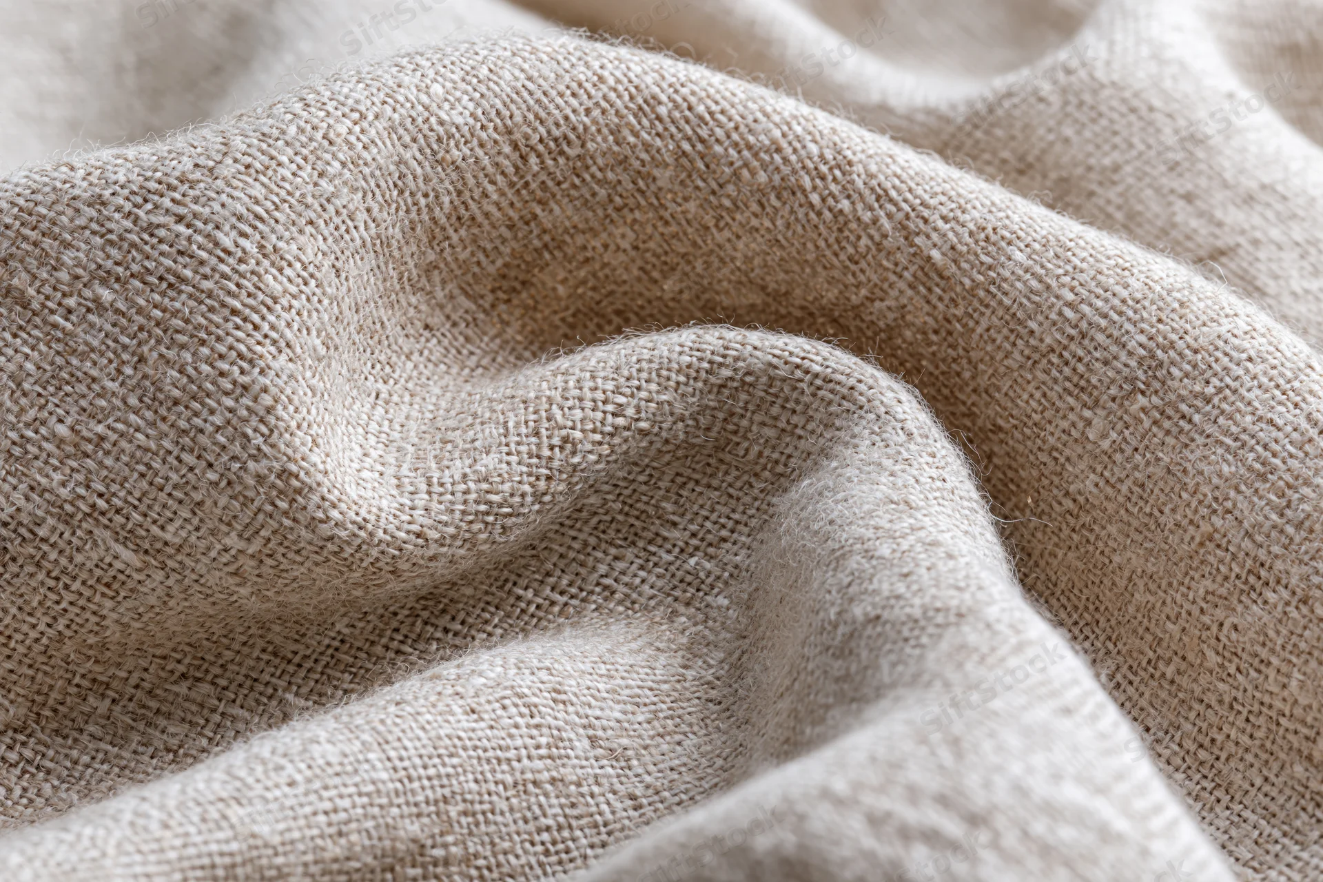 Close-up of natural linen fabric with visible weave and soft folds filling the frame