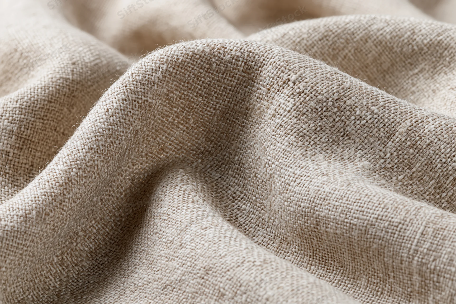 Close-up of natural linen fabric with visible weave and soft folds filling the frame