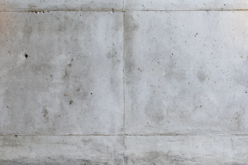 Close-up of a weathered concrete wall with visible seams and surface imperfections