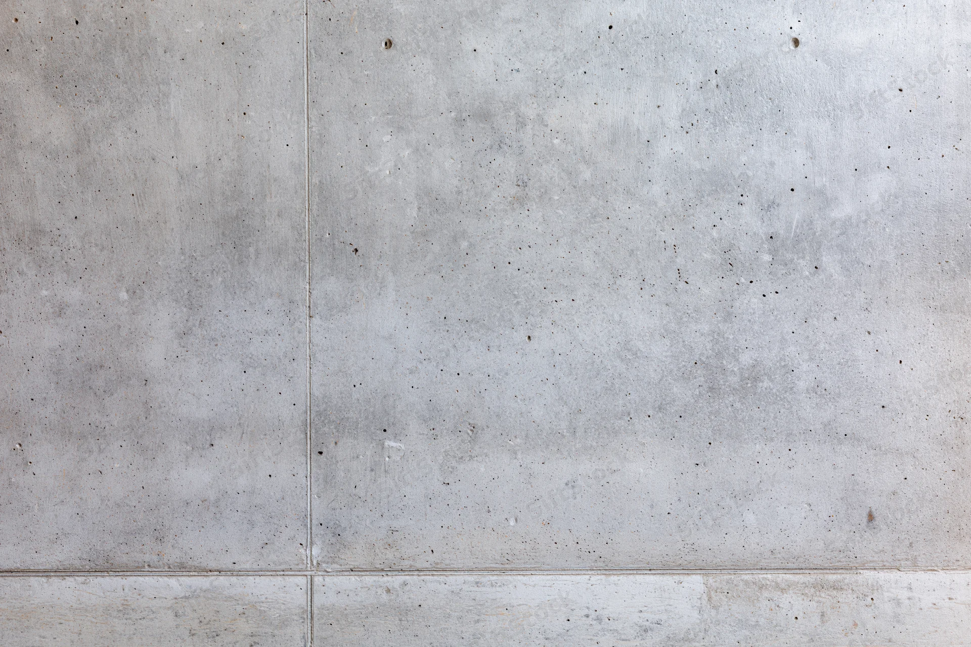 Close-up of a bare concrete wall filling the frame with visible seams and speckled texture